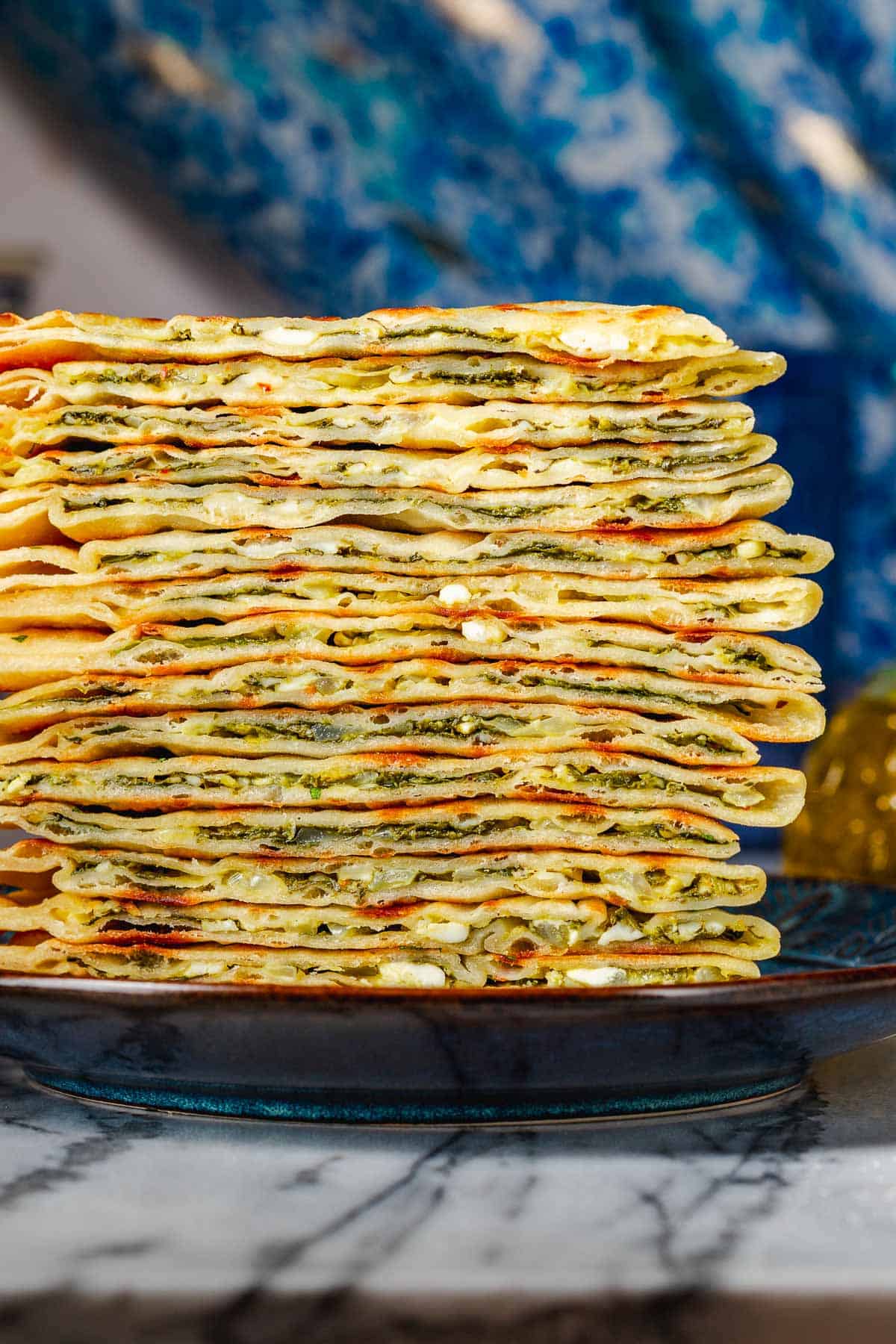 several gozleme turkish flatbread triangles stacked on a blue plate.