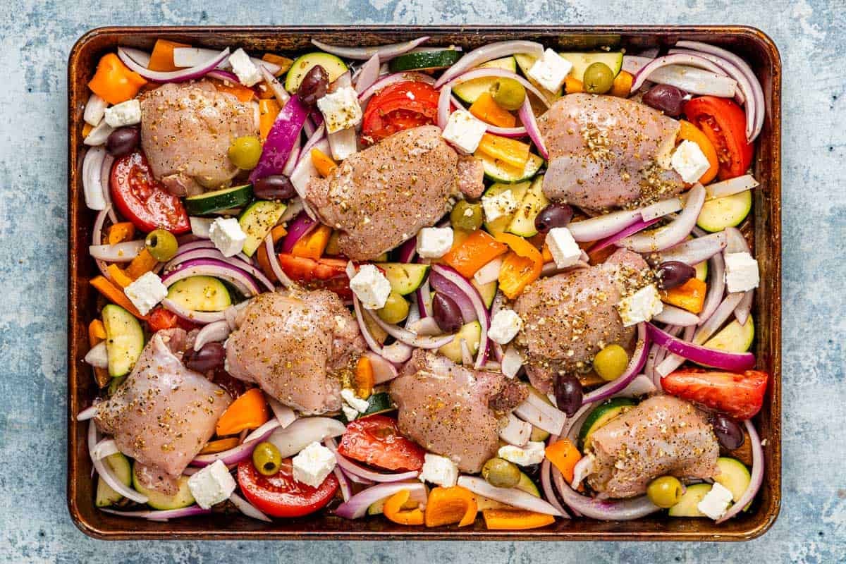 overhead photo of uncooked Greek sheet pan chicken and vegetables.