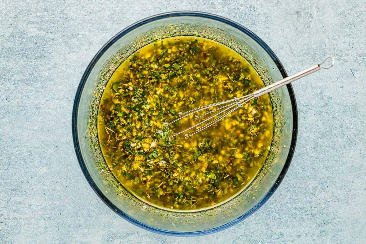 marinade for lemon garlic chicken in a glass bowl with a metal whisk.