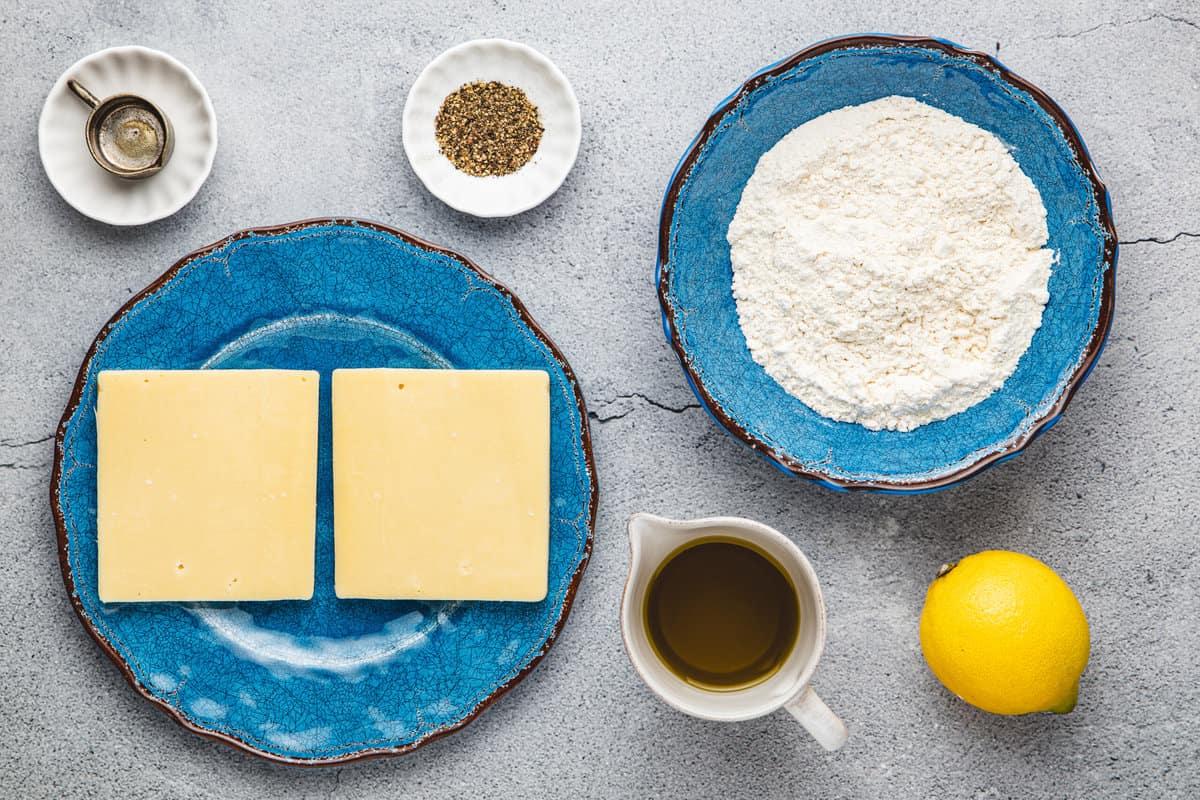 ingredients for saganaki fried greek cheese including 1 thick slices of cheese, flour, olive oil, lemon, black pepper and ouzo.