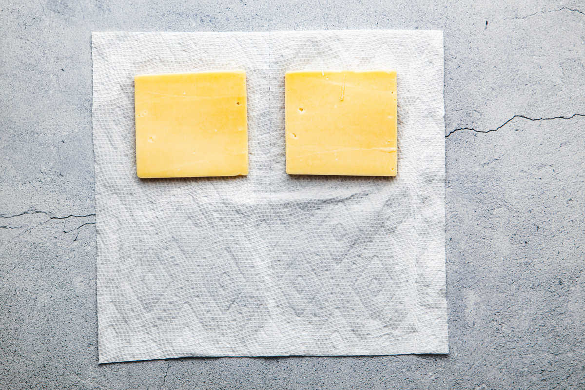 two thick slices of cheese sitting on a paper towel.