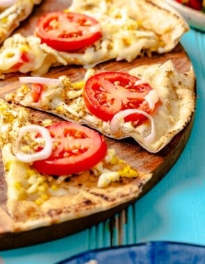 a pita breakfast pizza on a wooden serving platter sliced into individual pieces.