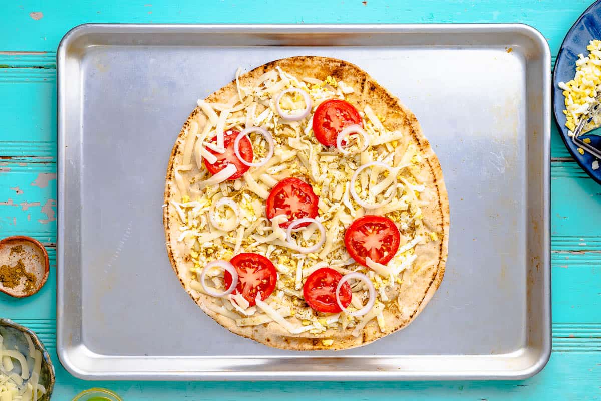 an unbaked pita breakfast pizza on a sheet pan.