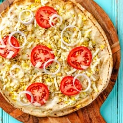 overhead photo of a baked pita breakfast pizza on a wooden serving platter.