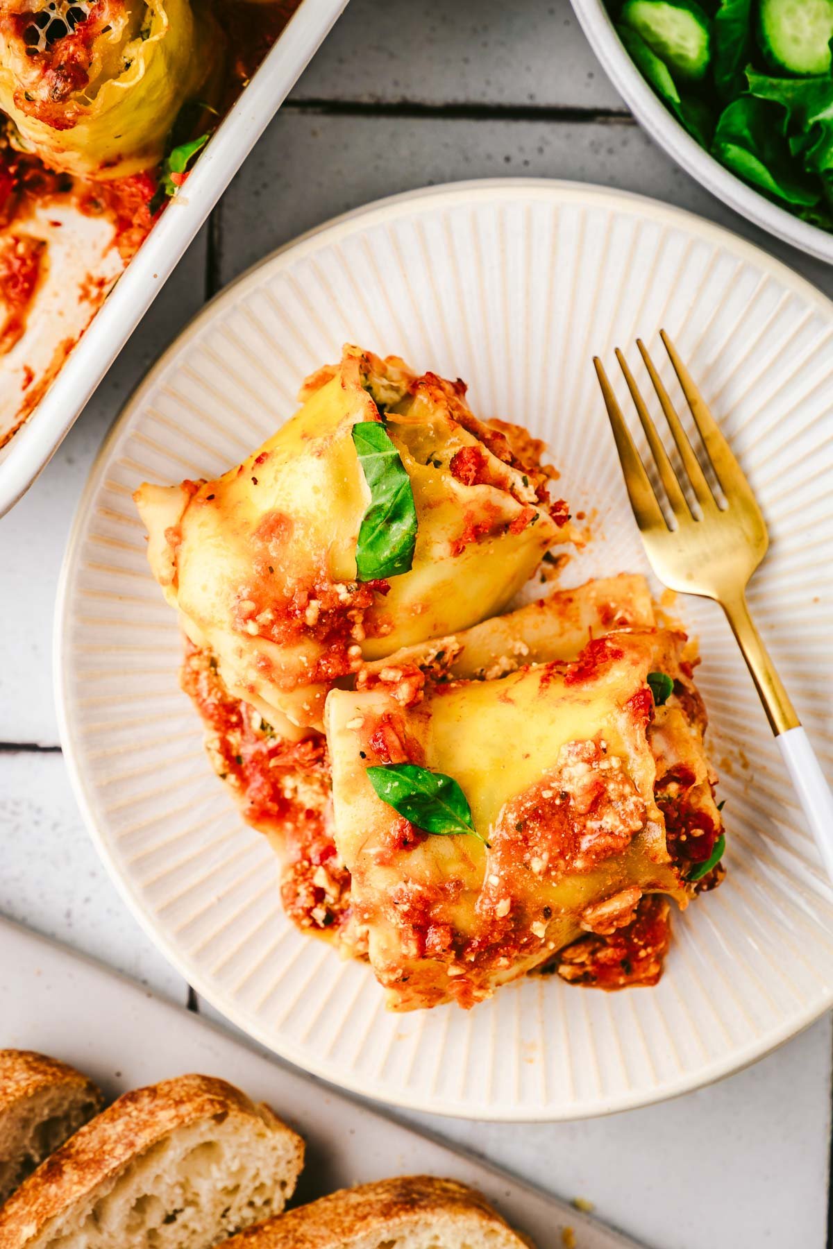 two lasagna roll ups on a white plate with a fork.