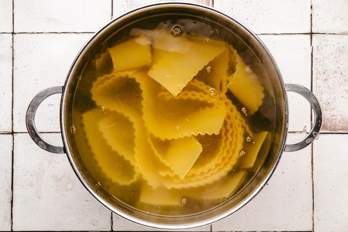 lasagna noodles boiling in a pot of water.