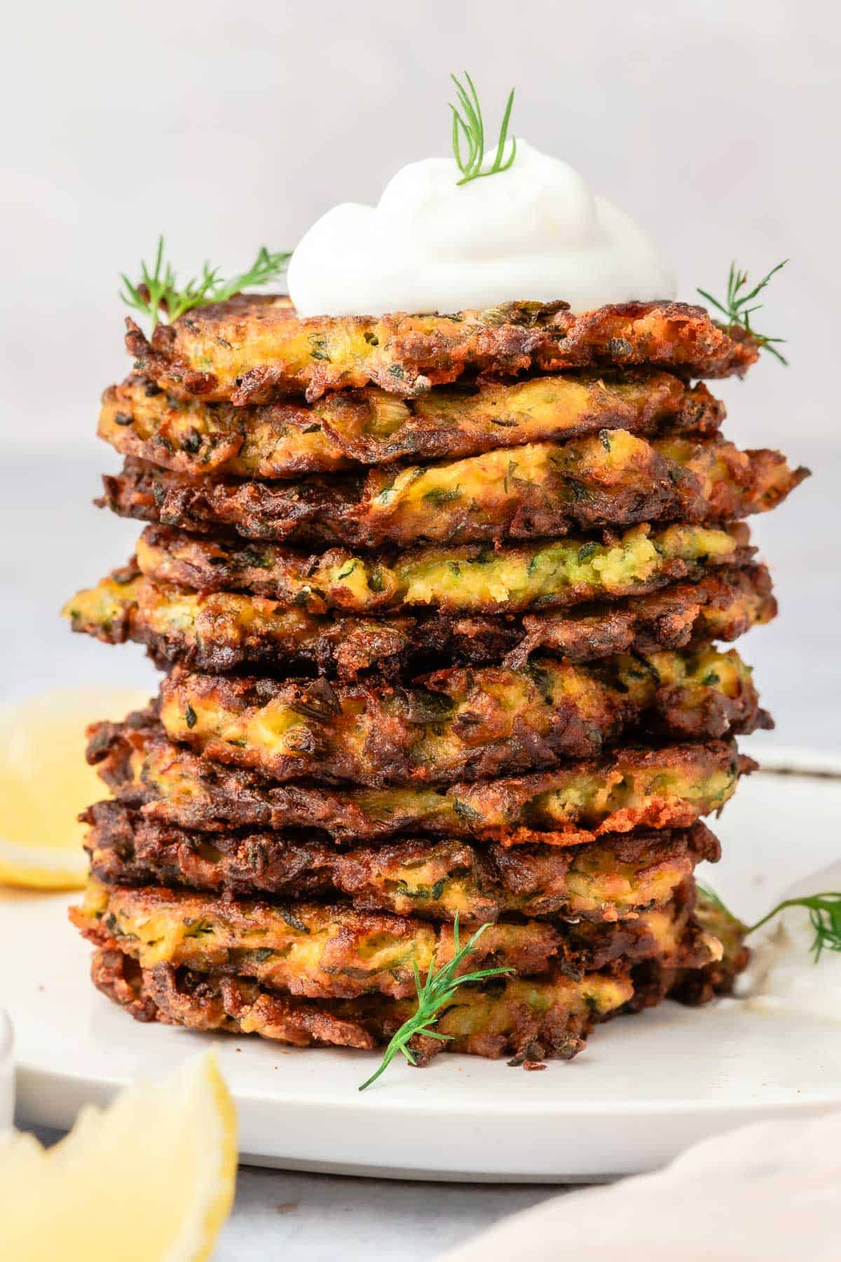 Stack of zucchini fritters with a dollop of greek yogurt on top.