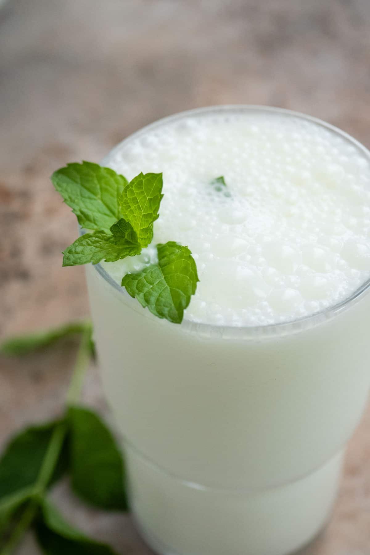 an ayran turkish yogurt drink in a glass garnished with mint leaves.