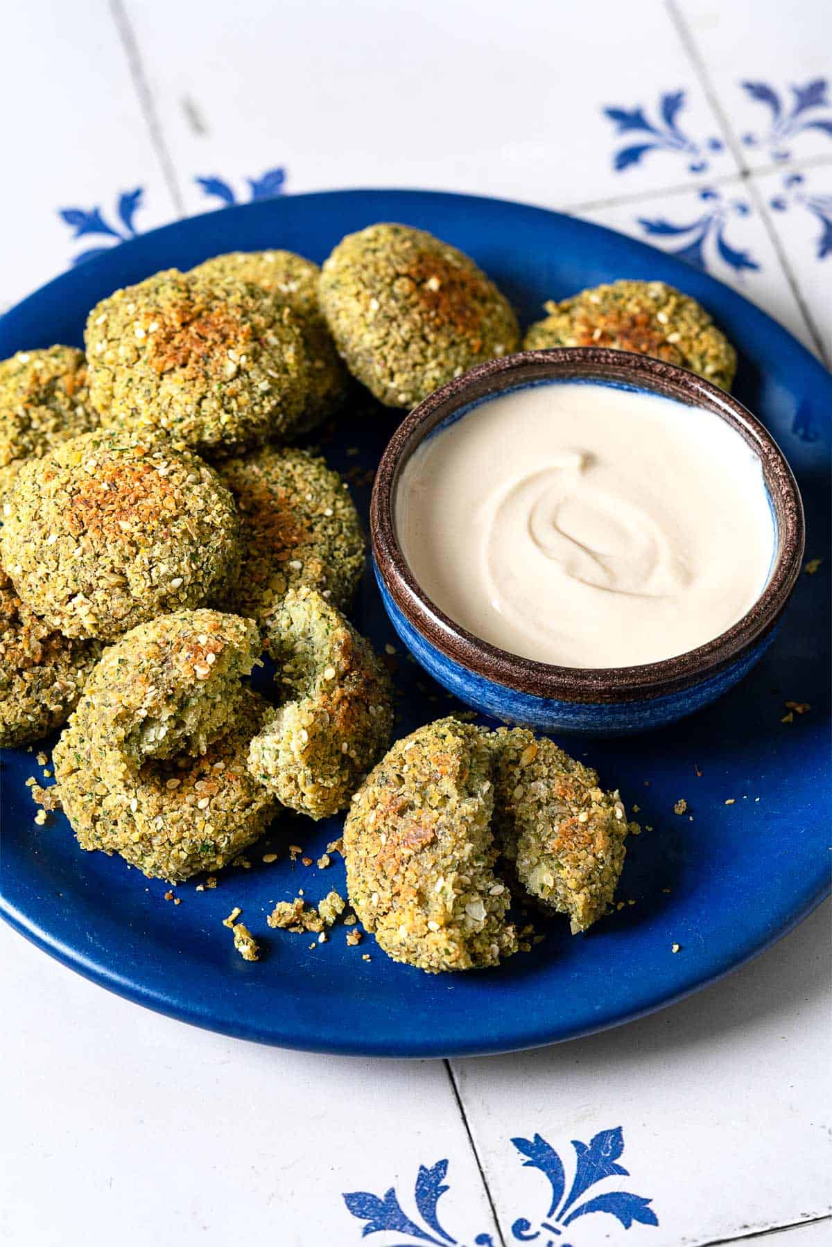a plate of baked falafel with a small bowl of tahini sauce.