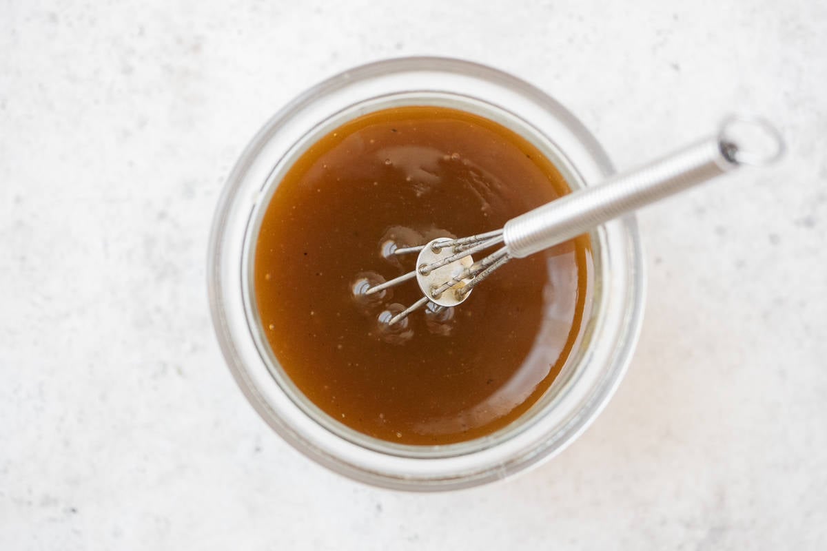 overhead photo of honey balsamic vinaigrette in a jar with a whisk.