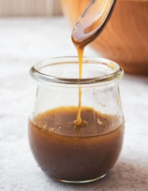 honey balsamic vinaigrette being drizzled from a small serving spoon into a jar of balsamic vinaigrette.