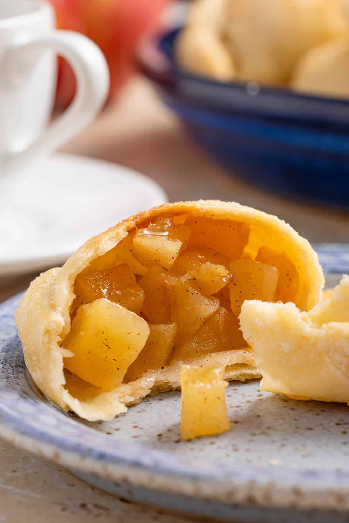 a close up of an apple empanada half on a small blue plate.