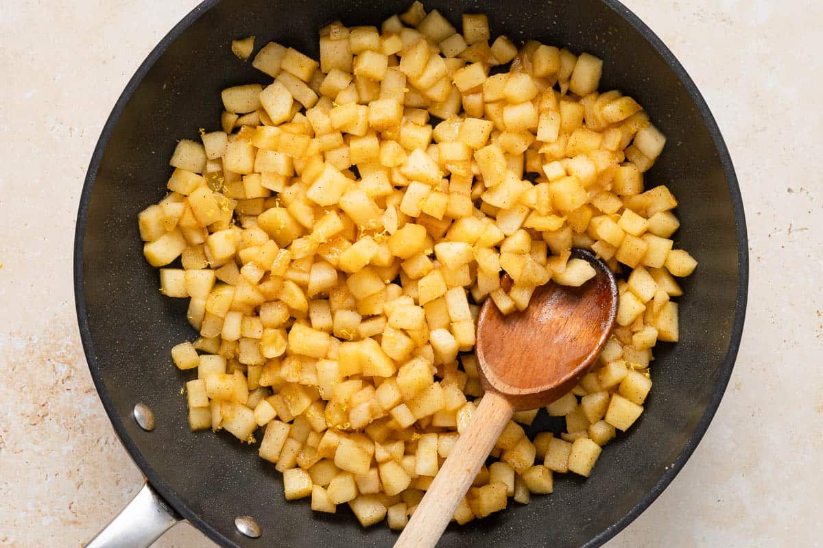 apple filling being cooked in a skillet with a wooden spoon.