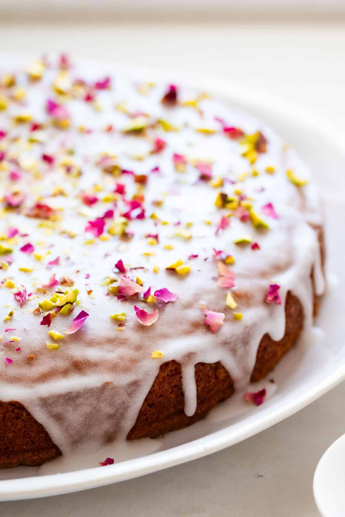 A close up shot of Persian love cake with rose petals and pistachios sprinkled over top.