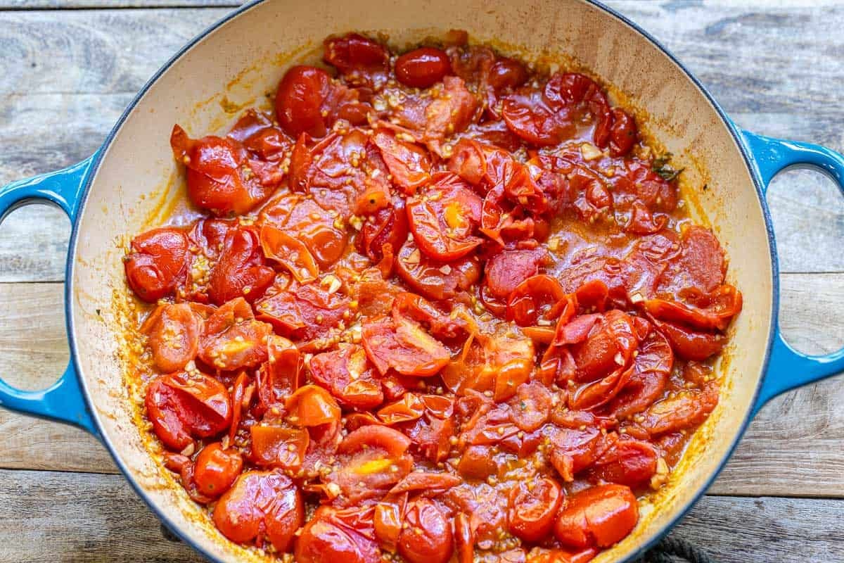 stewed cherry tomatoes in a blue skillet.