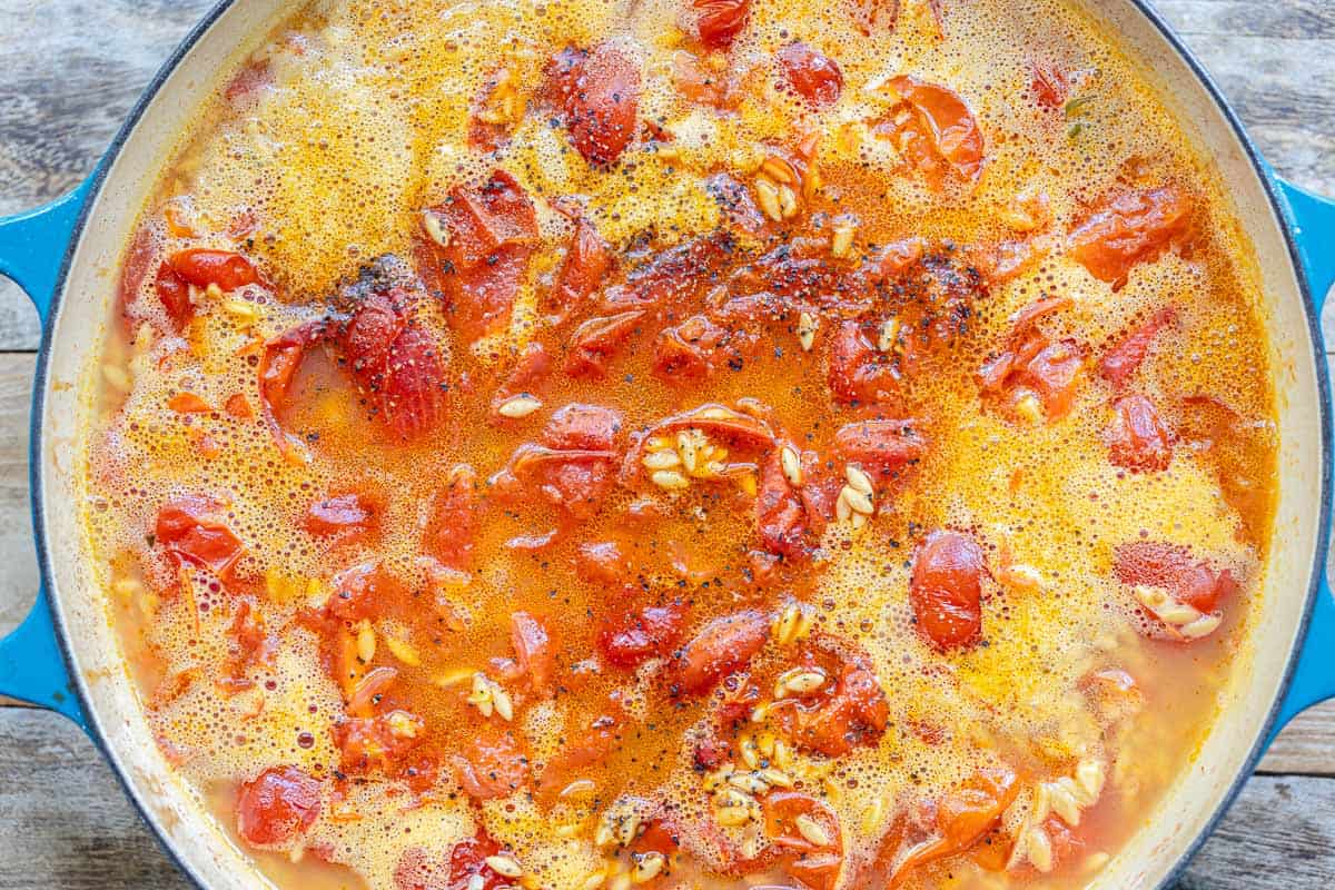 creamy orzo simmering in a blue skillet.