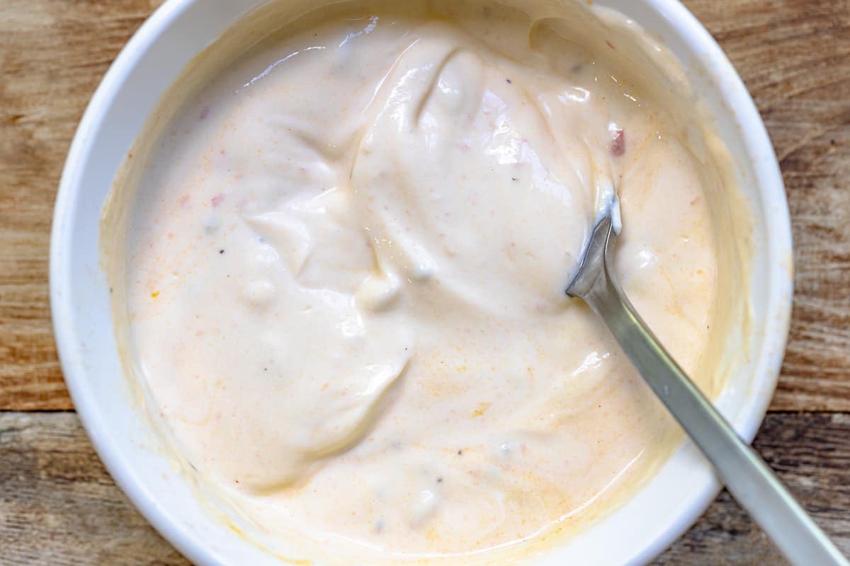 tempered greek yogurt in a white bowl with a spoon.