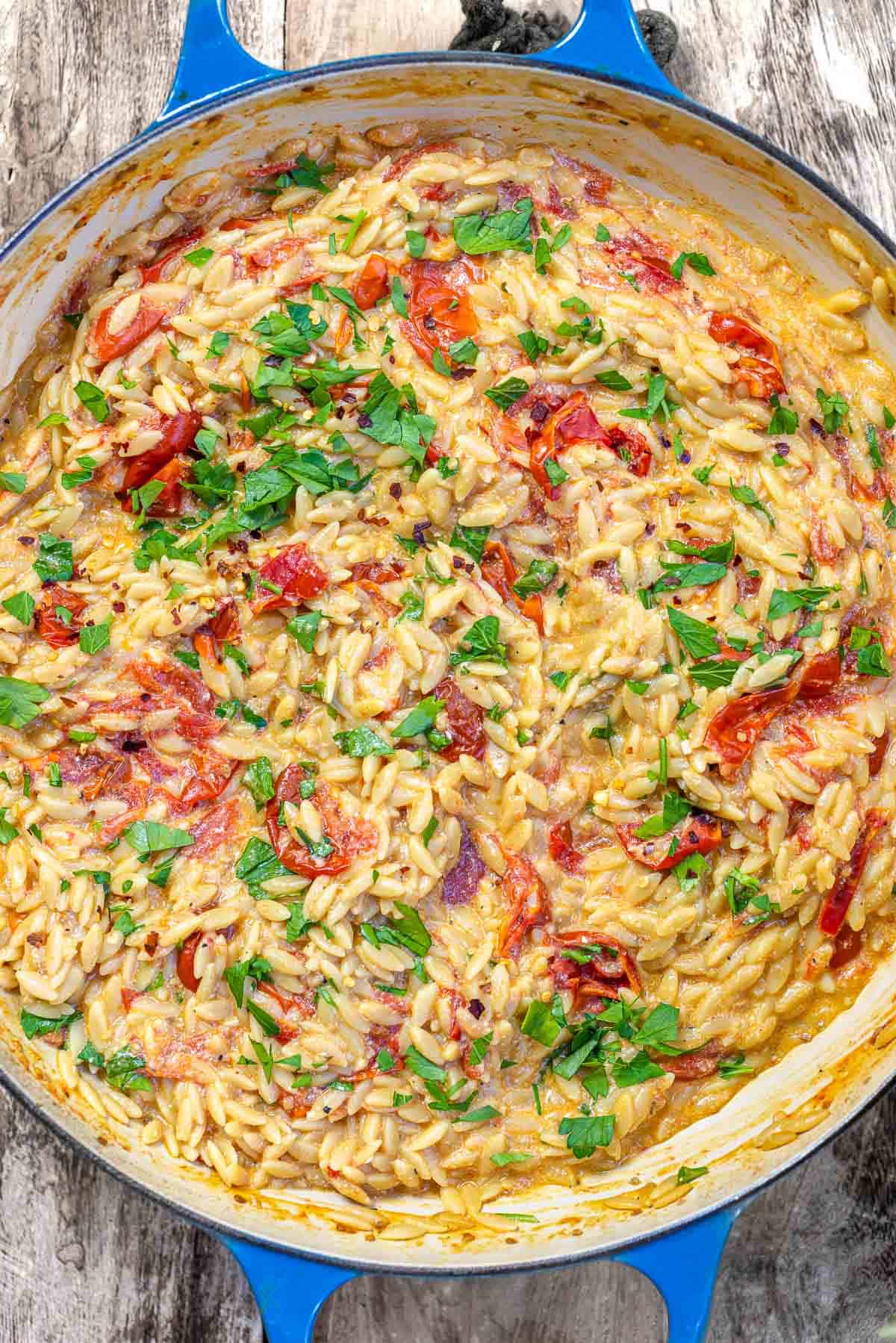 overhead photo of creamy orzo in a blue skillet.