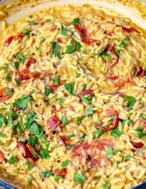 close up photo of creamy orzo in a blue skillet.