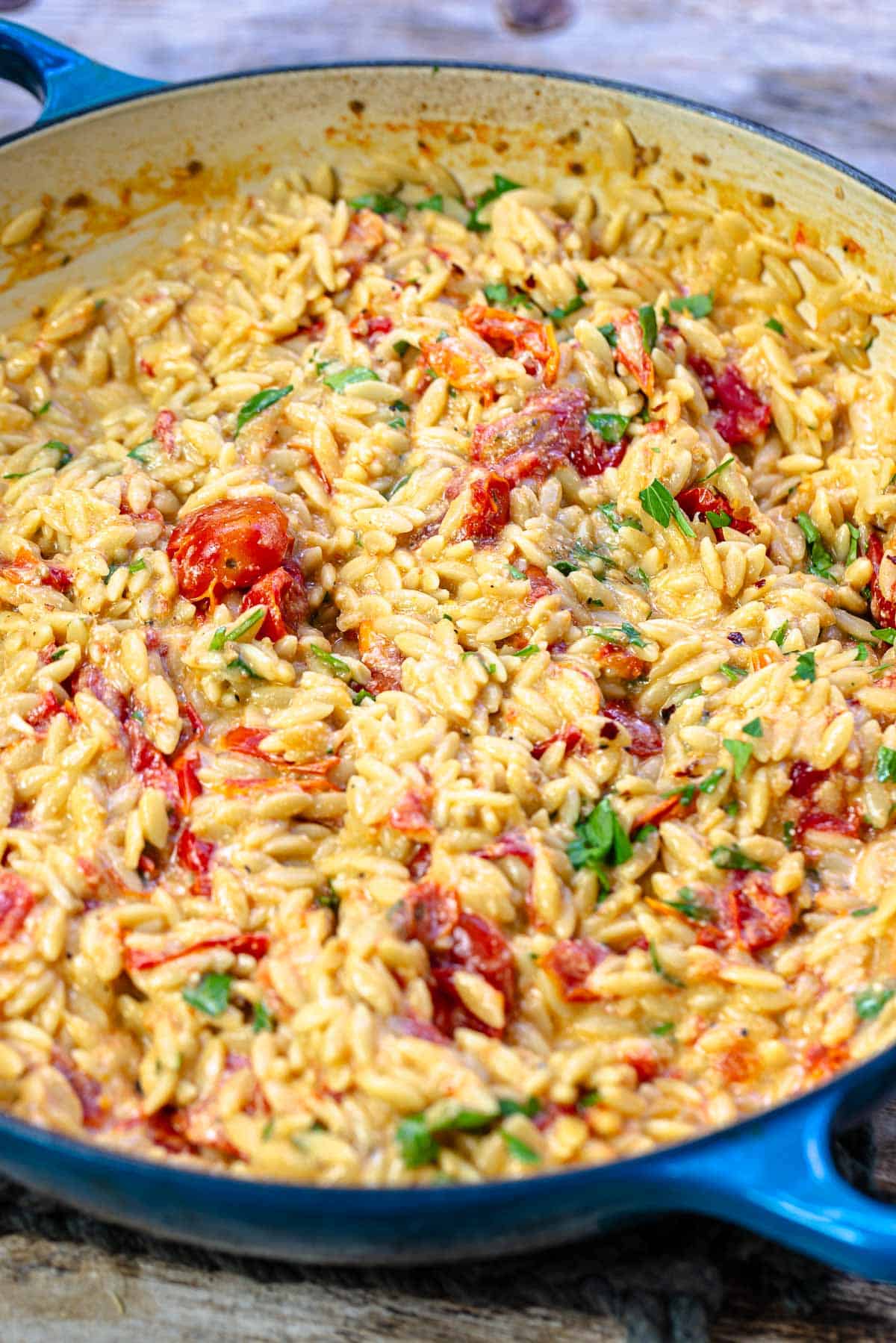 a close up of creamy orzo in a blue skillet.