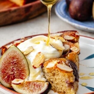 Honey being drizzled on a slice of fig cake.