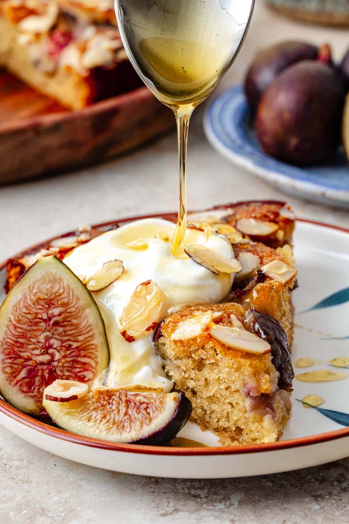 Honey being drizzled on a slice of fig cake.