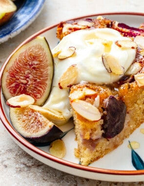 slice of fig cake on a plate with Greek yogurt and sliced almonds on top.