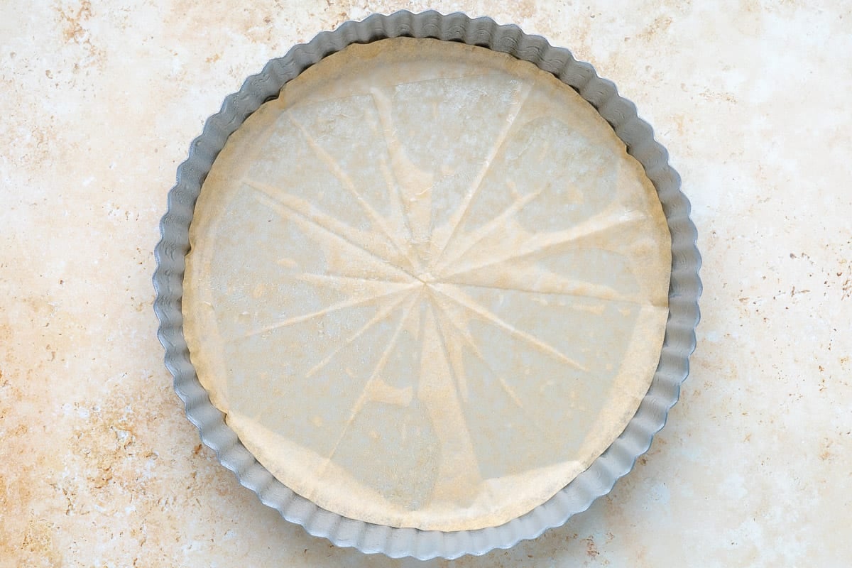 A tart shell that's been oiled and lined with parchment paper.