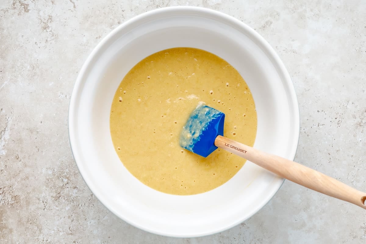 Fig cake batter being stirred in a bowl with a rubber spatula.
