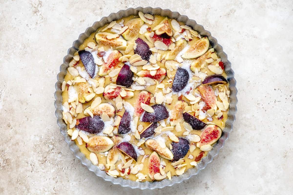 Fig cake in a tart shell before being baked, with a sprinkle of sugar on top.