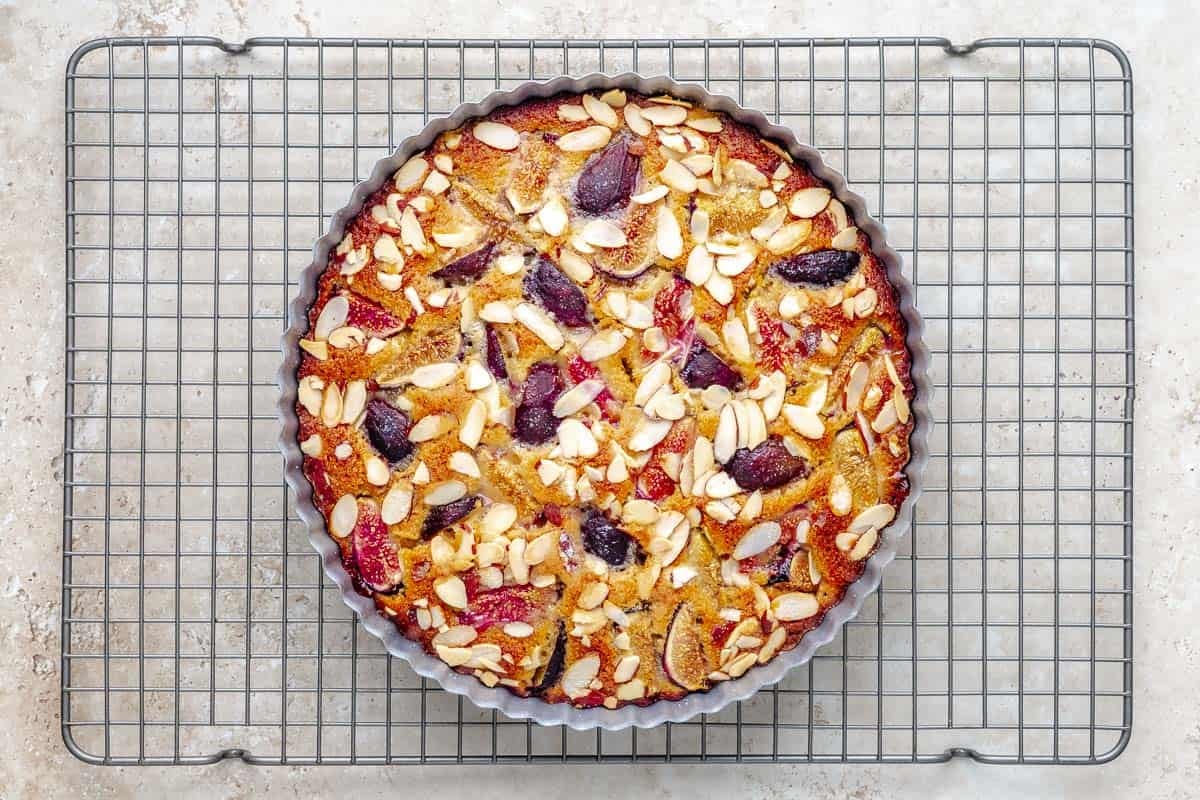 Overhead shot of fig cake cooling in a tart shell on a wire rack.