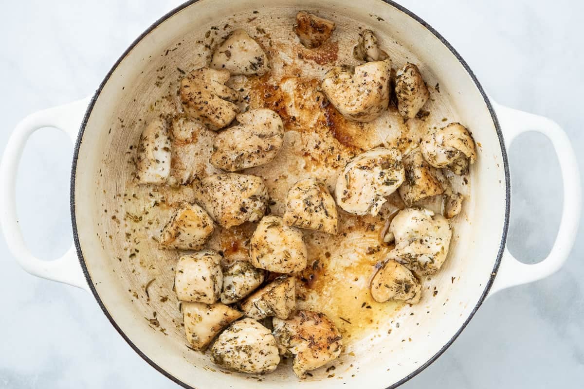 morceaux de poitrine de poulet assaisonnés d'assaisonnements italiens cuisant dans une casserole.