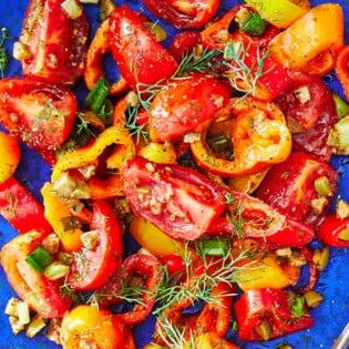 close up of a serving of bell pepper salad on a blue plate.