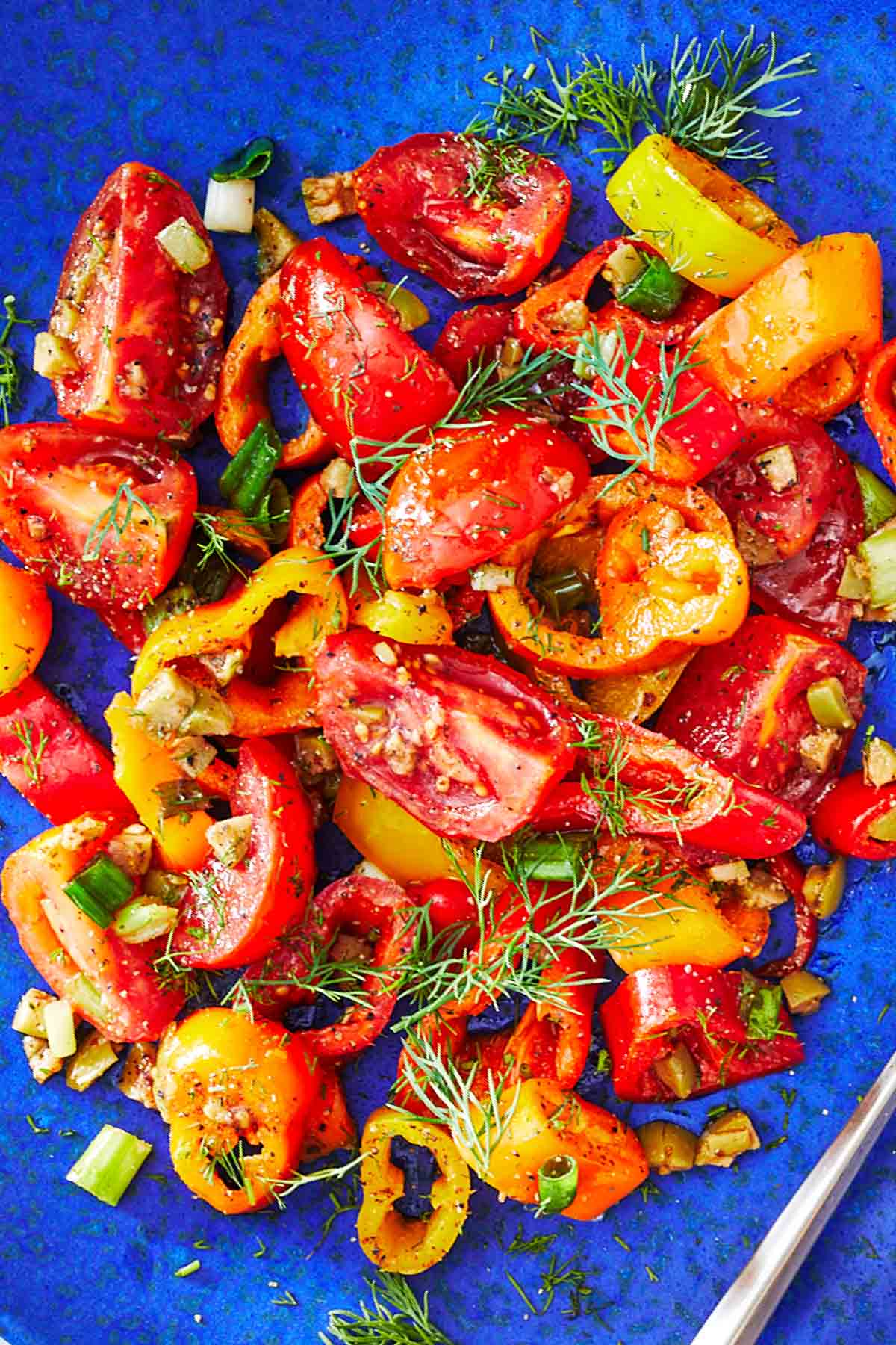 close up of a serving of bell pepper salad on a blue plate.