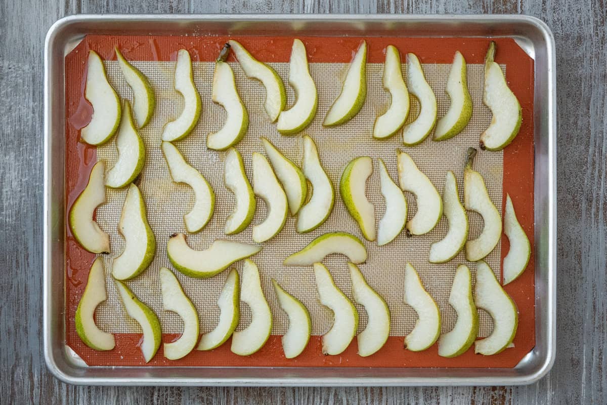 un-roasted pear wedges on a line baking sheet.