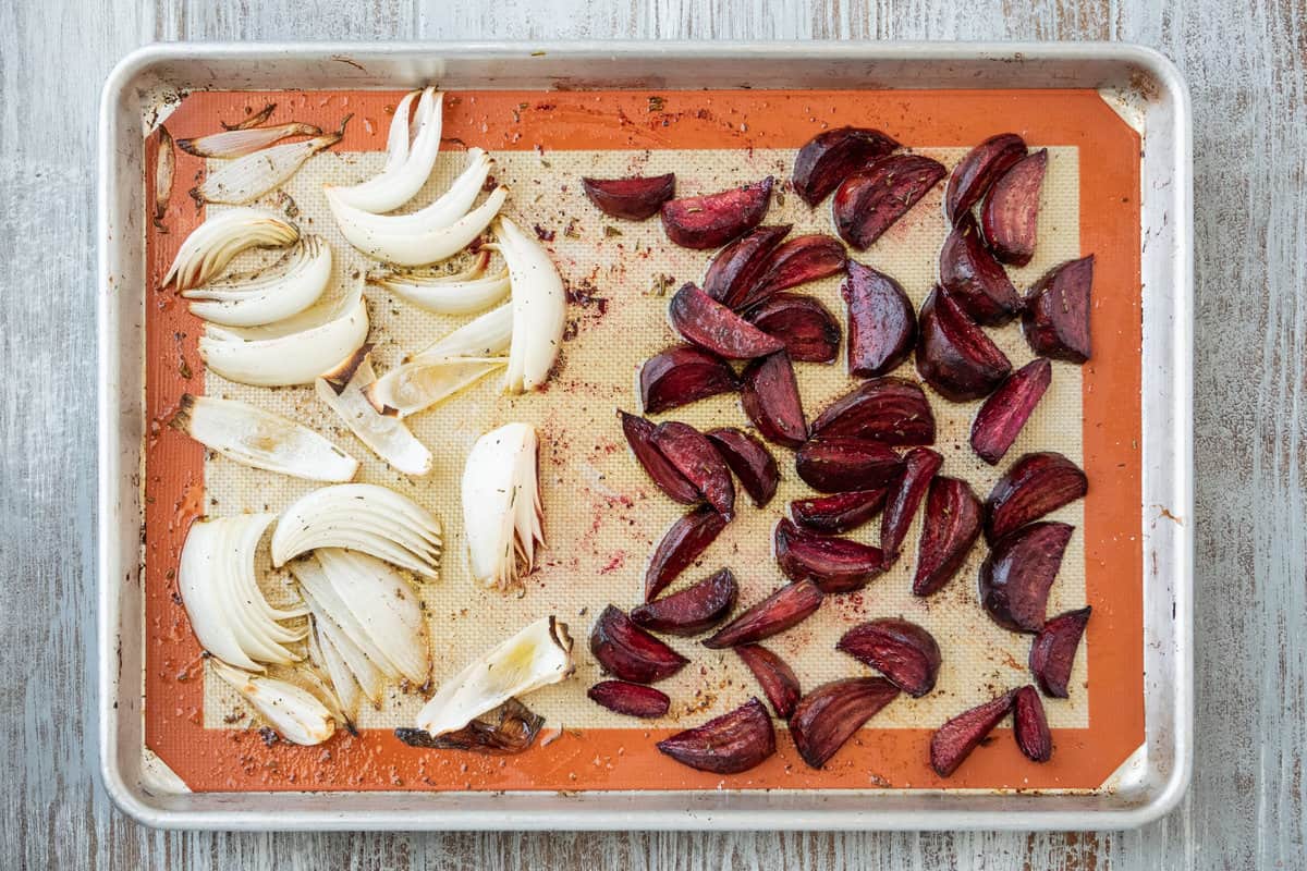 roasted onion and beet slices on a lined baking sheet.