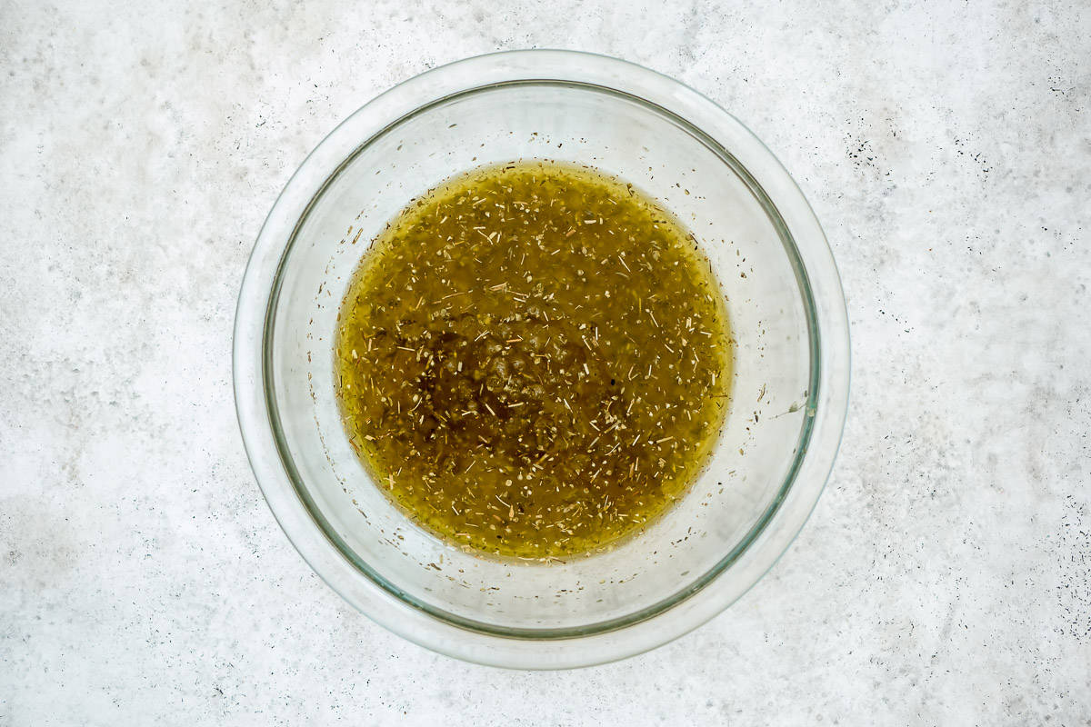 a citrus, honey, thyme and oregano sauce in a clear mixing bowl.