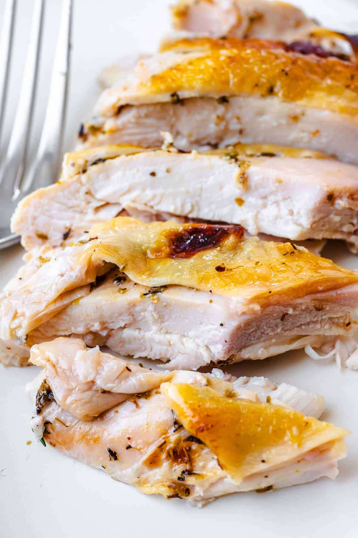 close up of a piece of sliced roast spatchcock chicken next to a fork.