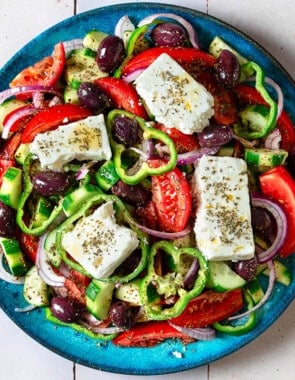 Overhead photo of a Greek salad on a blue serving platter.