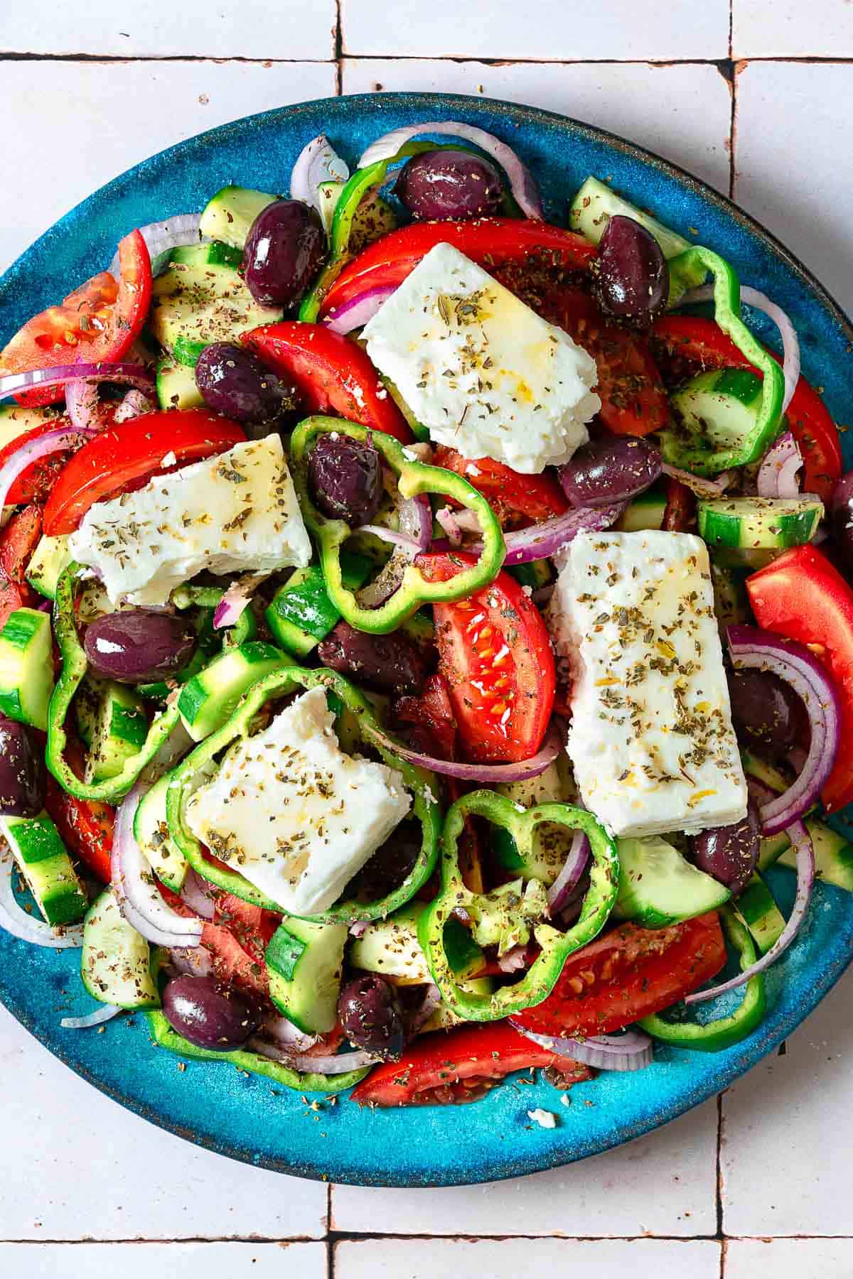 close up overhead photo of a Greek salad on a blue serving platter.