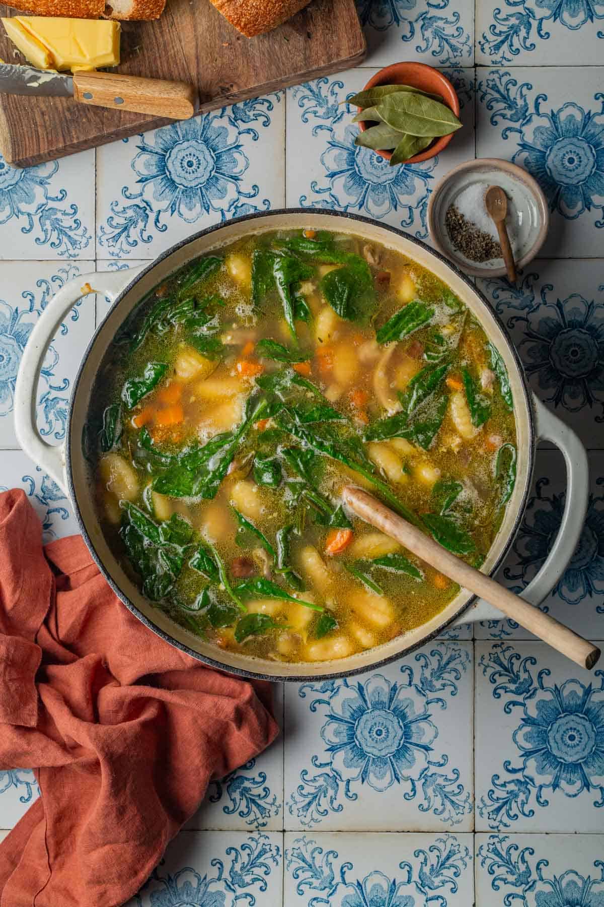 A pot of chicken gnocchi soup showing a healthy amount of wilted spinach.