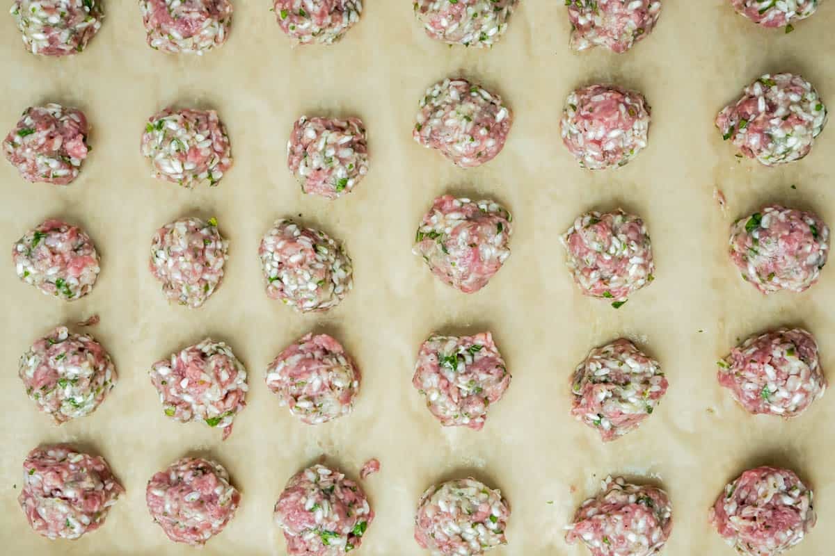 uncooked meatballs on a sheet of parchment.