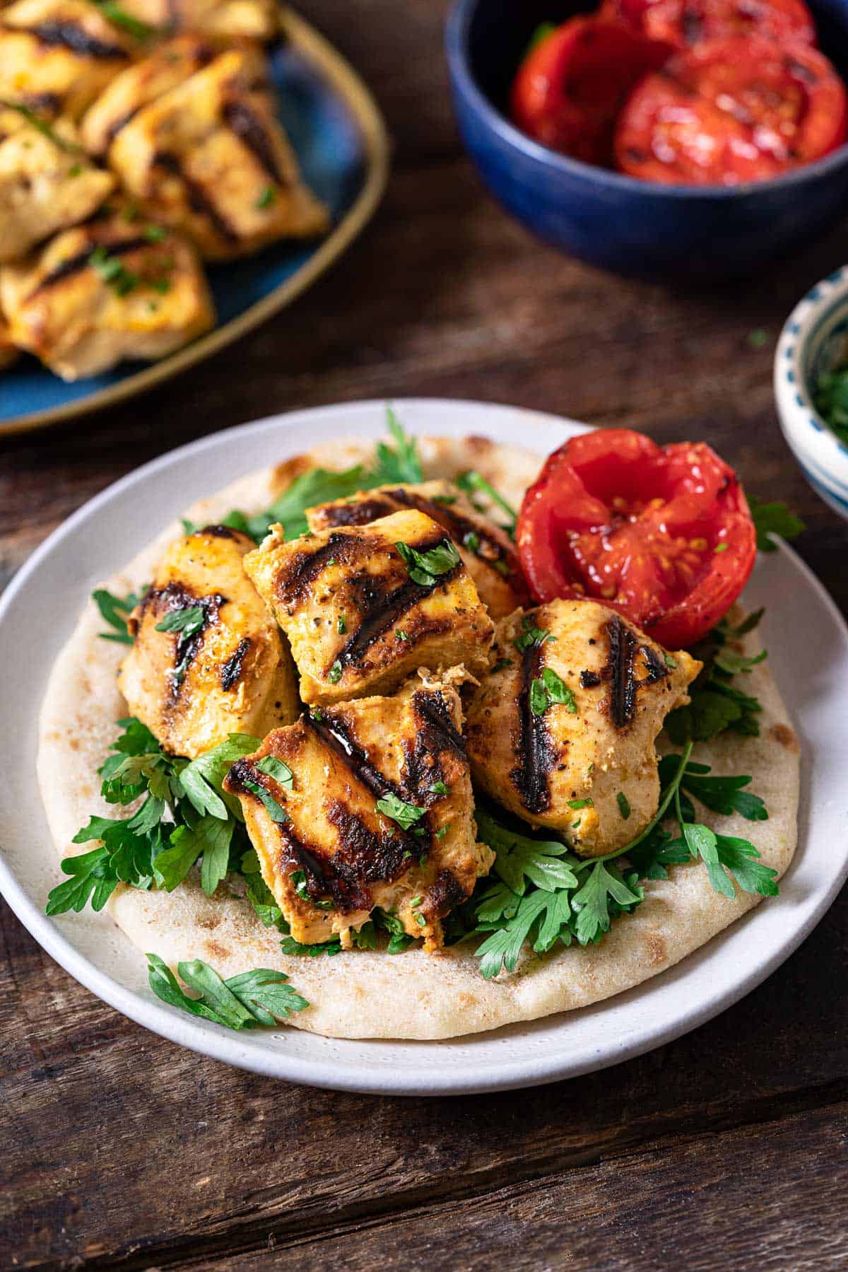 chicken from the joojeh kabobs on a pita garnished with tomato and parsley.