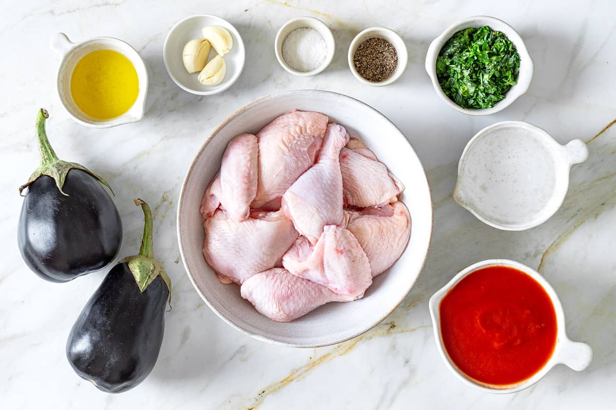 ingredients for Braised Chicken and Eggplant including chicken, eggplant, tomato puree, white wine, garlic, chopped herbs, salt, pepper and olive oil.