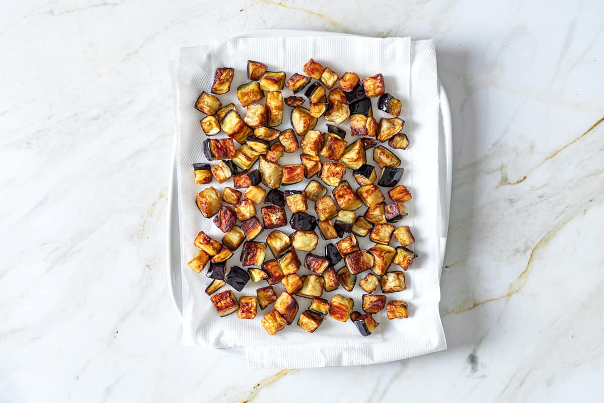 fried cubes of eggplant on a paper towel-line platter.