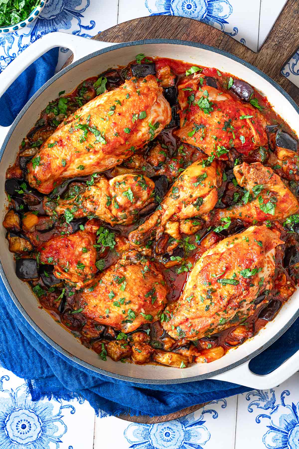 cooked Braised Chicken and Eggplant in a skillet on a wooden serving tray.