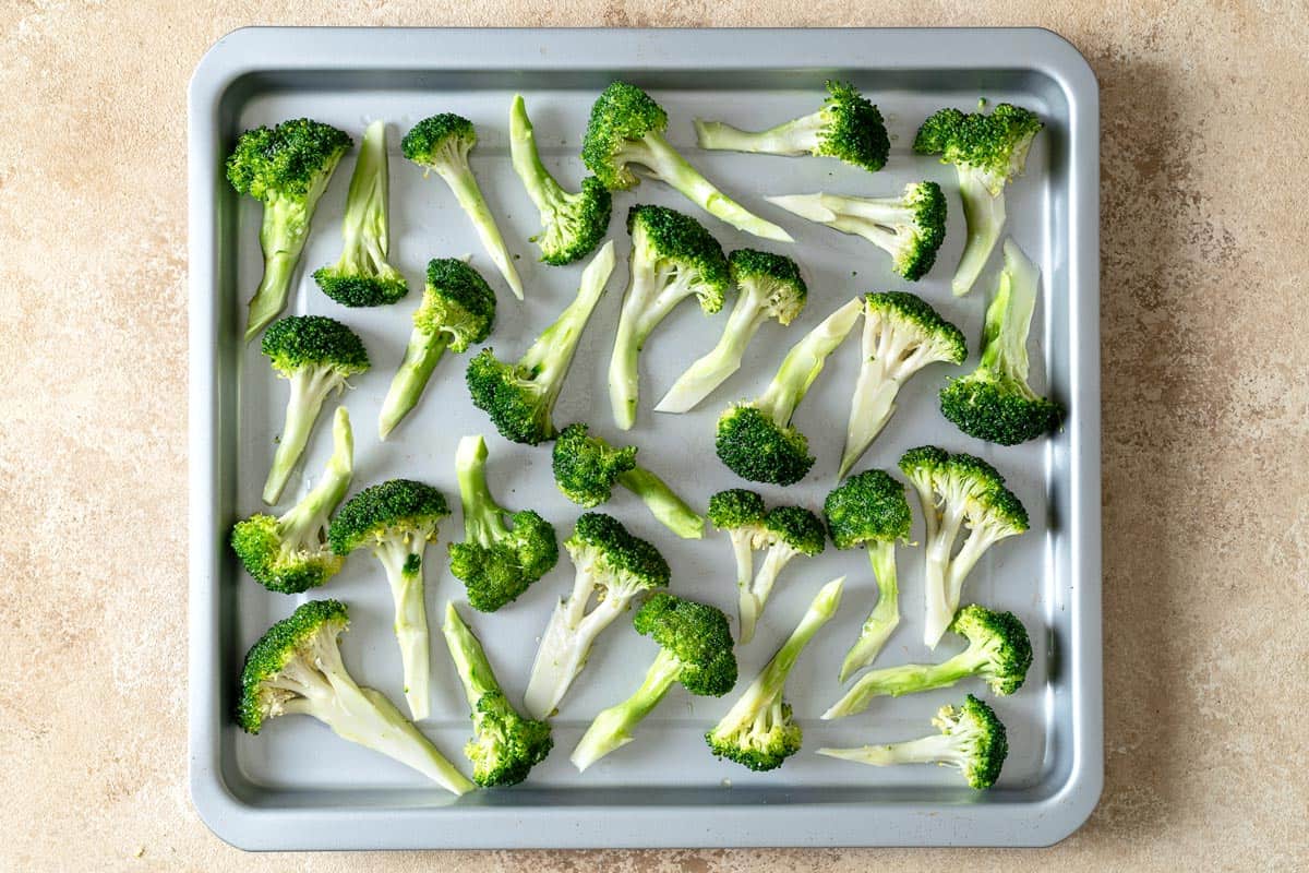 pieces of uncooked broccoli on a sheet pan.