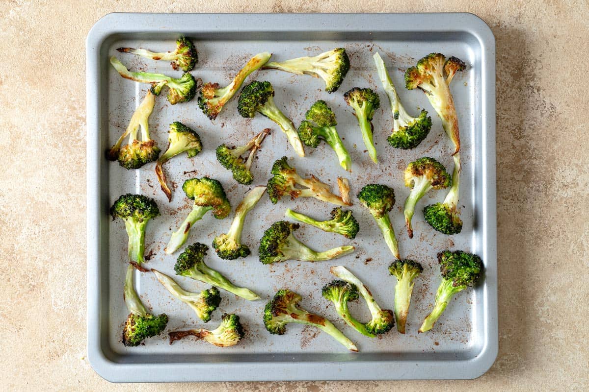 Pieces of roasted broccoli on a sheet pan.