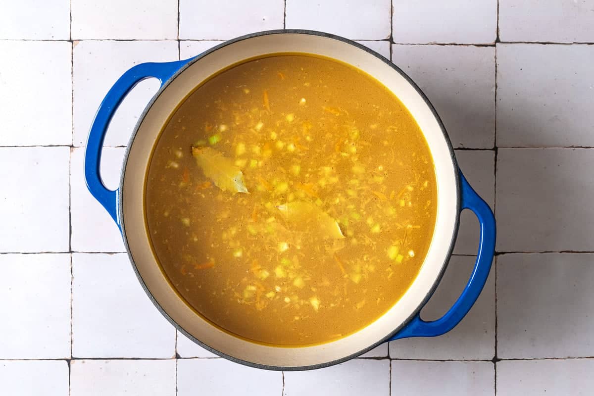 barley, vegetables and bay leaves simmering in a pot of chicken stock.