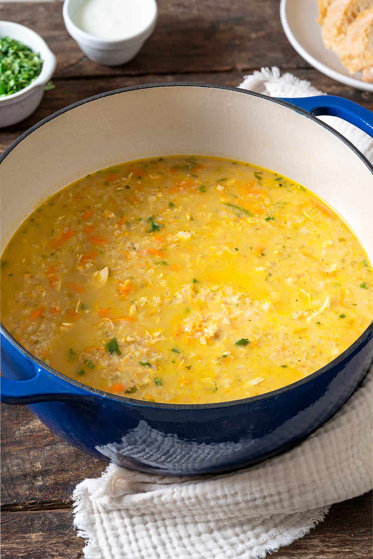 soupe jo in a large post surrounded by small bowls of chopped parsley and cream, and a plate of sliced crusty bread.